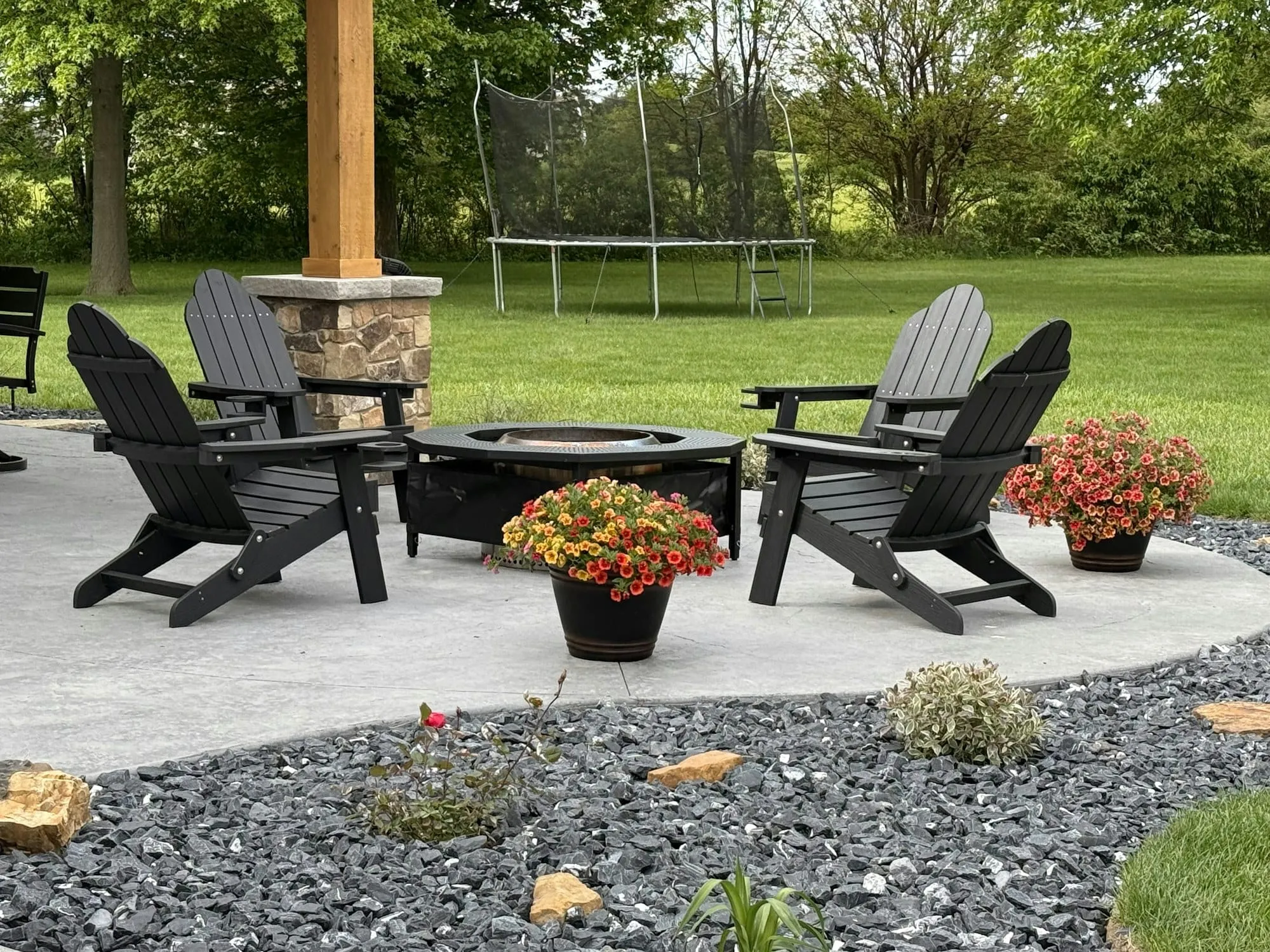 Backyard patio with Adirondack chairs, fire pit and flowers