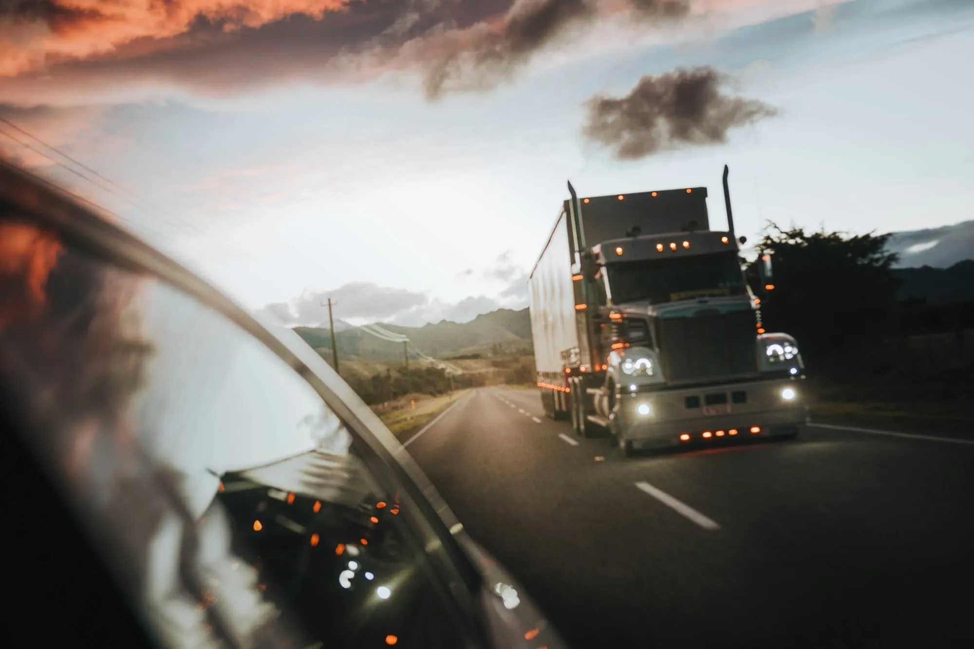 Semi truck driving down a highway at sunset